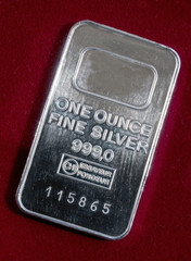 The surface of minted silver bar weighing one troy ounce. The texture of the surface of the silver ingot. Against the background of burgundy velvet.