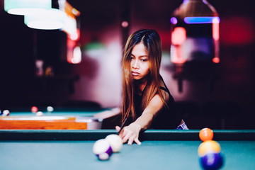 Young beautiful girl playing billiard in a club