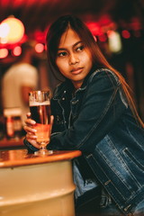 Young beautiful woman drinking beer in a bar