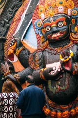Foto auf Leinwand A man and woman place offerings at the foot of this depiction of Kala Bhairav in Durbar Square, Kathmandu. © raphoto