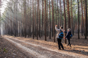 mother and son stroll through the fabulous pine forest into the light,Mother and baby walk on country rural road in pine forest