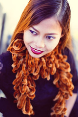 Fototapeta premium Young beautiful girl in black dress with brown scarf sitting on the bench