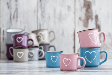 Colorful Cute Coffee Mugs with Hearts on White Wooden Background