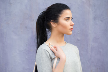 Stylish woman with bag at violet wall