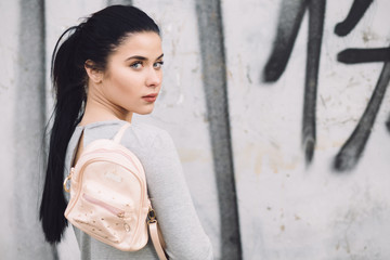 Stylish woman portrait with bag at a street wall