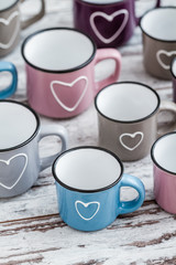Colorful Cute Coffee Mugs with Hearts on White Wooden Backgrounds