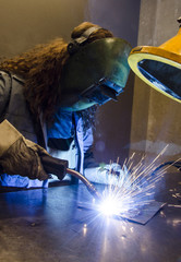 Woman welding in the metal industry - obrazy, fototapety, plakaty