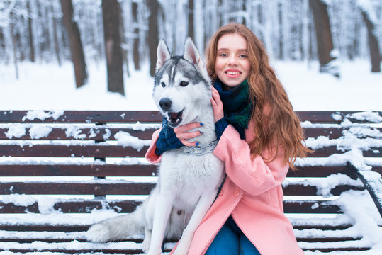 Happy woman sitting on the bench with husky