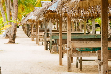 Fototapeta premium Nipa huts on the white coral sand beach surounded with palms
