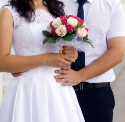 Obraz na płótnie Canvas Bride and groom holding wedding bouquet with roses