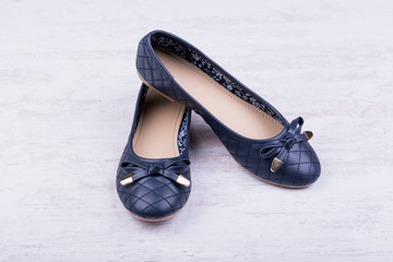 Pair of dark blue ladies' flat shoes on white wooden background