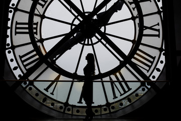 Woman silhouette standing in front of large clock