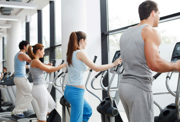 People exercising on cardio machines in the gym.