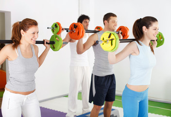 Group of people lifting barbells in weight training class.