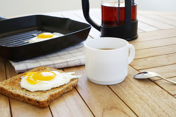 Fried eggs with toast and coffee on the wooden table, top view