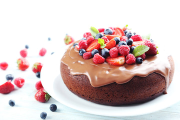 Homemade chocolate cake with berries on white wooden table