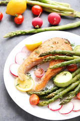 Steak of salmon with asparagus and vegetables on grey wooden table