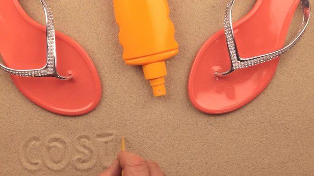 Costa del Sol inscription written by hand on the sand, among beach accessories.