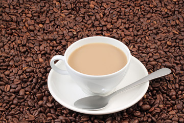 A white coffee cup on a background of whole coffee beans