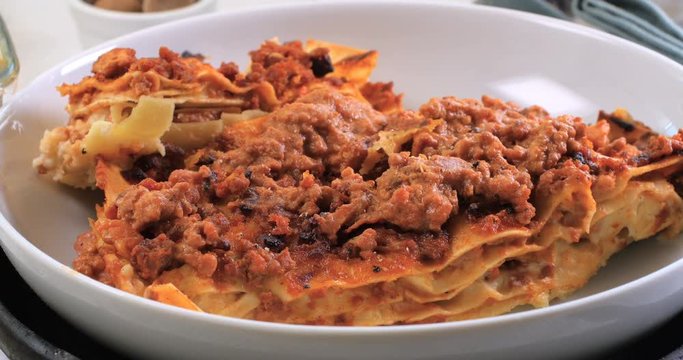 Sprinkling black pepper over delicious steamy lasagne in bolognese sauce