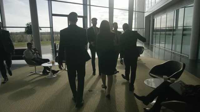  2 Business groups meet & shake hands in modern glass office building