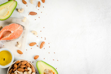Healthy food. Products with healthy fats. Omega 3, omega 6. Ingredients and products: trout (salmon), flaxseed oil, avocado, almonds, cashews, pistachios. On a white stone table. Copy space top view