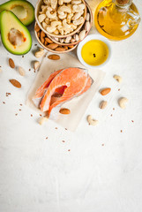 Healthy food. Products with healthy fats. Omega 3, omega 6. Ingredients and products: trout (salmon), flaxseed oil, avocado, almonds, cashews, pistachios. On a white stone table. Copy space top view