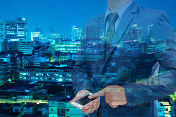 double exposure of business man using tablet with night modern city building background