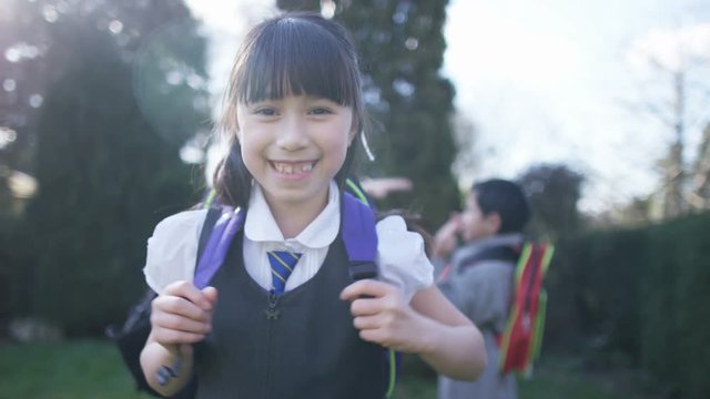 Portrait of smiling little girl with backpack, outdoors in school playground