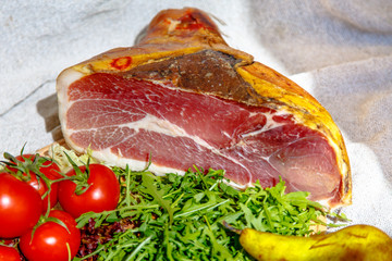 Italian prosciutto is on the counter with arugula and tomatoes.
