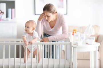 Depressed young woman with cute baby at home