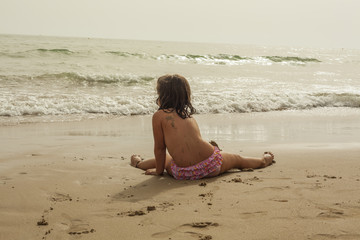 Fototapeta na wymiar Rear view girl wearing pink swimsuit in the seashore of the beach. Sunset