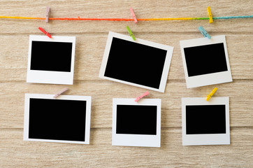 empty photo frames hanging with clothespins on wooden background