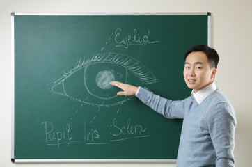 Handsome young Asian teacher near blackboard