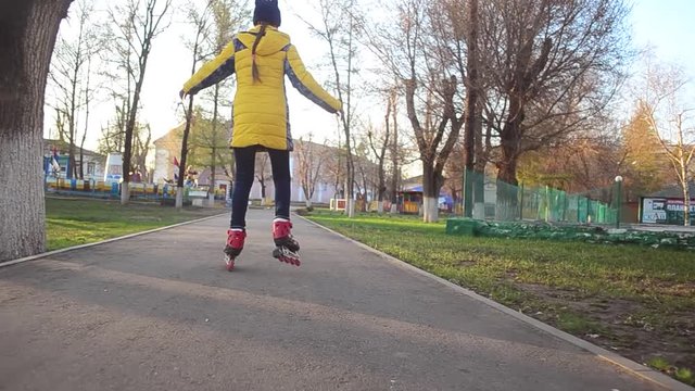 teen girl learns to roller skate in Park in spring