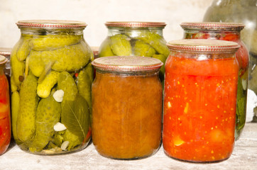Dusty glass jars with canned fruits and vegetables in storage.