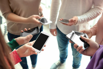 Young people standing in circle and using smartphones