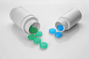 Cough drops spilling out of bottles on white background