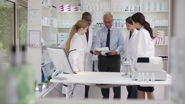  Friendly team of staff in a chemists shop chatting & discussing their work