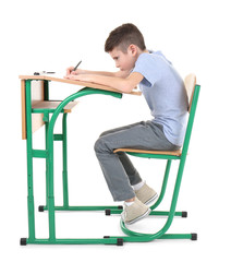 Incorrect posture concept. Cute schoolboy sitting at desk on white background