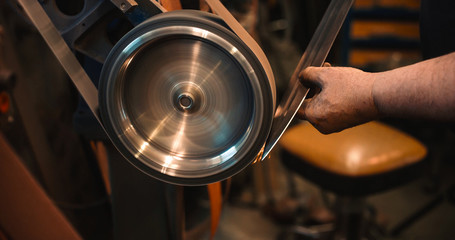 Craftsman uses a belt sander in machine shop.
