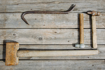 Rusty tools sledgehammer, nailer and two hammers lie on old boards background with copy space for text, top view, flat lay, time concept