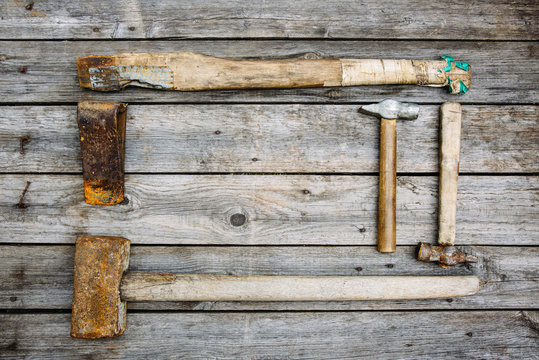Rusty tools sledgehammer, ax and two hammers lie on old boards background with copy space for text, top view, flat lay, time concept