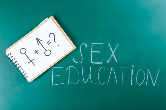Exercise book with male and female symbols near text SEX EDUCATION on chalkboard