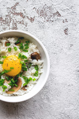 Tamago Kake Gohan. Healthy korean vegan food. Boiled white rice with raw yolk and green onion on concrete background. Top view. Vertical photo 