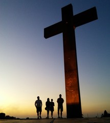 People walk by a cross sign in Praça do Papa (Pope's square) in Belo Horizonte, Brazil. In this...