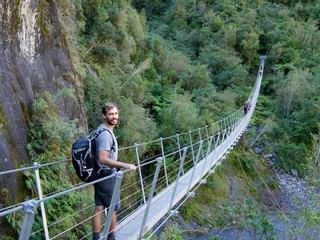 Naklejka premium Male hiker standing on swing bridge