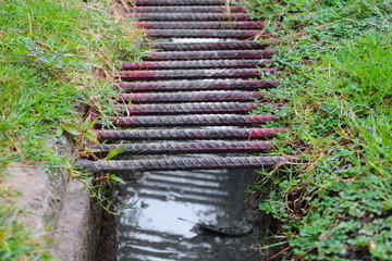 steel on water drain or ditch metal grid in floor grass select focus with shallow depth of field.