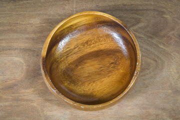 Empty round wooden bowl on wooden table, food display montage, top view.