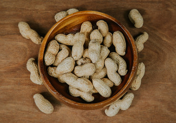 Peanuts in shell in a wooden bowl, selective focus (vintage filter).